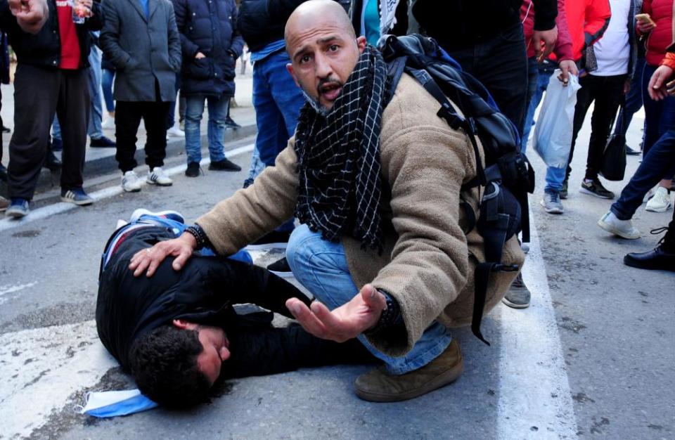 A demonstrator takes care of a man wounded by police in Tunis on 23 January.