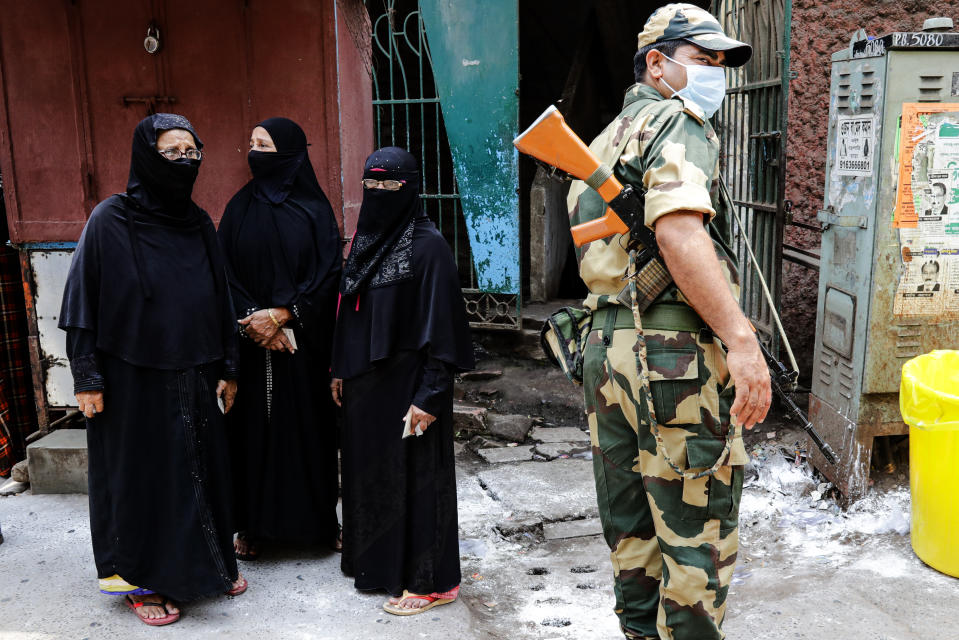 A paramilitary soldier stands guards as voters wait to cast their votes at a polling station during the fourth phase of West Bengal state elections in Kolkata, India, Saturday, April 10, 2021. (AP Photo/Bikas Das)