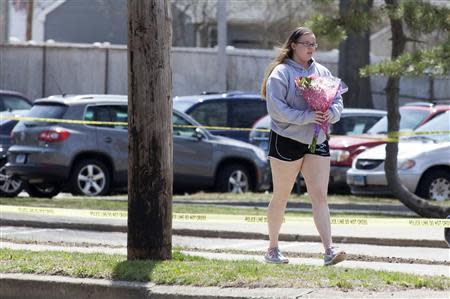 A girl walks with flowers in front of Jonathan Law High School in Milford, Connecticut April 25, 2014. REUTERS/Michelle McLoughlin