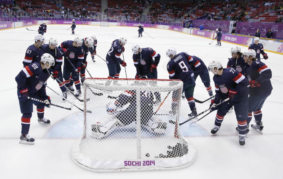 USA players gather around the net before the men's bronze medal ice hockey game against Finland at the 2014 Winter Olympics, Saturday, Feb. 22, 2014, in Sochi, Russia. (AP Photo/David J. Phillip)