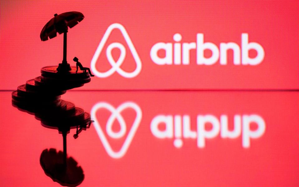 In this file photo illustration taken on August 29, 2018 in Paris on August 29, 2018, a toy umbella and a figurine on coins sre seen next to the logo of rental website Airbnb - Joel Saget/AFP