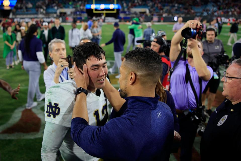 Notre Dame quarterback Tyler Buchner (left) celebrates the Irish victory in the 2022 TaxSlayer Gator Bowl with coach Marcus Freeman.
