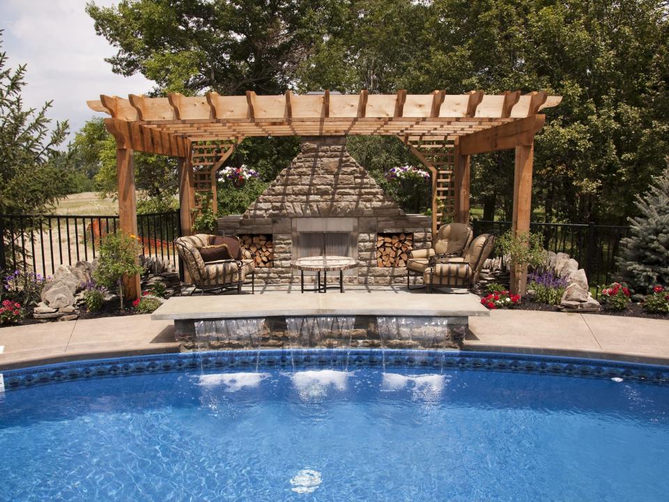 backyard with a inground pool and a pergola with furniture and a fireplace underneath