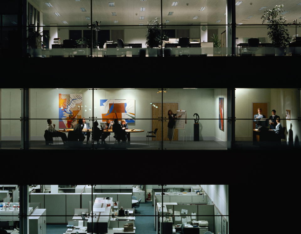 Executives in meeting, view through windows of office block at night