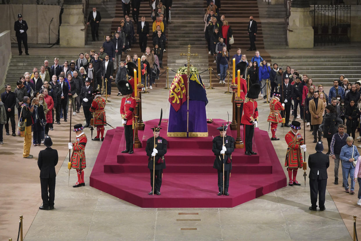 The final members of the public pay their respects at the coffin of Queen Elizabeth II, draped in the Royal Standard with the Imperial State Crown and the Sovereign's orb and sceptre, lying in state on the catafalque in Westminster Hall at the Palace of Westminster in London early Monday, Sept. 19, 2022.  (Yui Mok/Pool Photo via AP)