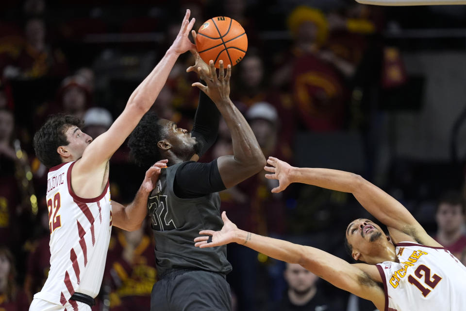 Oklahoma State center Mike Marsh (32) drives to the basket between Iowa State forward Milan Momcilovic, left, and forward Robert Jones (12) during the second half of an NCAA college basketball game, Saturday, Jan. 13, 2024, in Ames, Iowa. Iowa State won 66-42. (AP Photo/Charlie Neibergall)