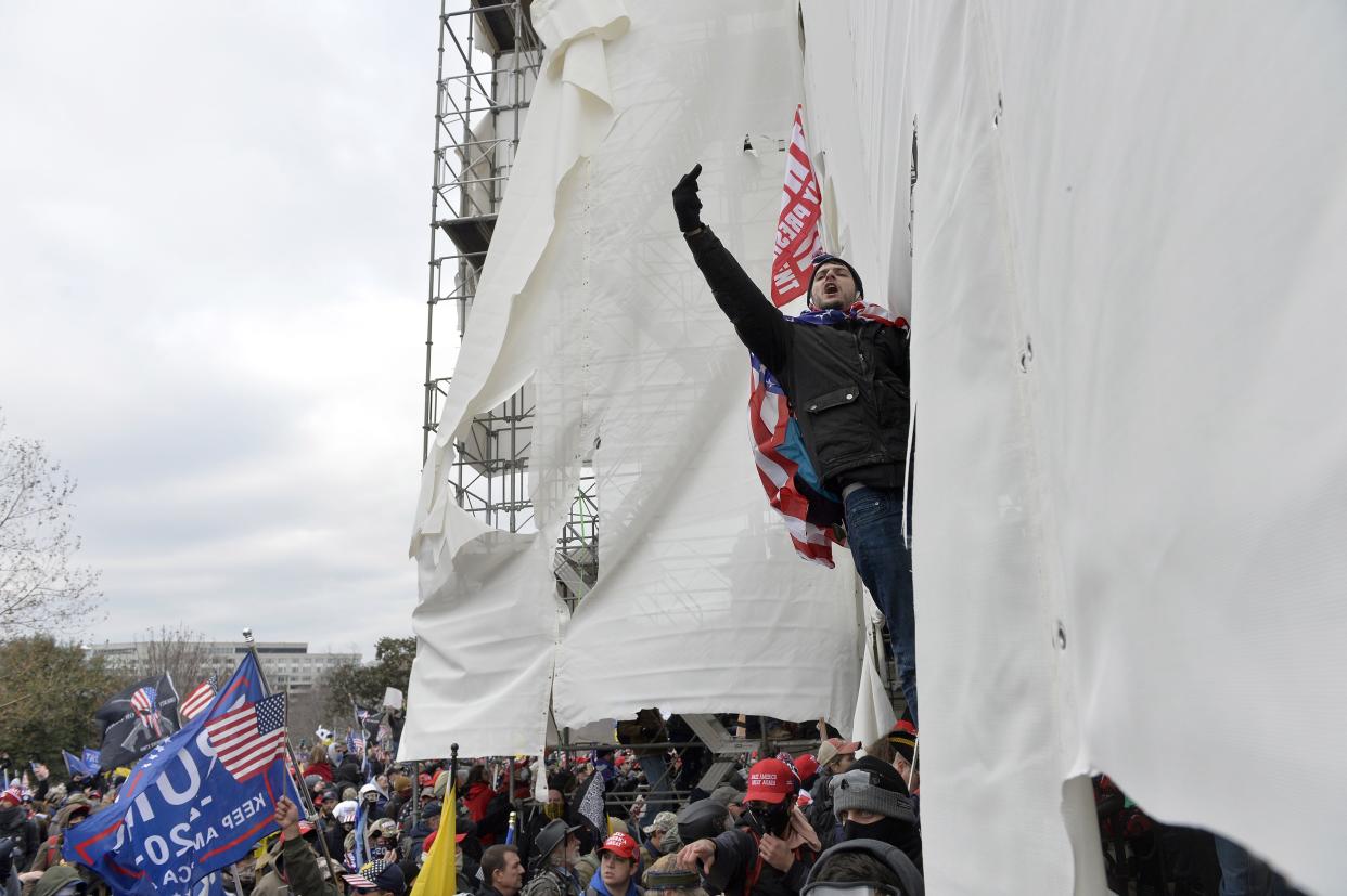 Trump supporters clash with police and security forces, climbing scaffolding as they try to storm the US Capitol in Washington D.C on January 6, 2021.