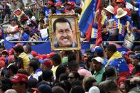 People hold a portrait of former Venezuelan president Hugo Chavez during a ceremony commemorating the second anniversary of his death in Caracas on March 5, 2015