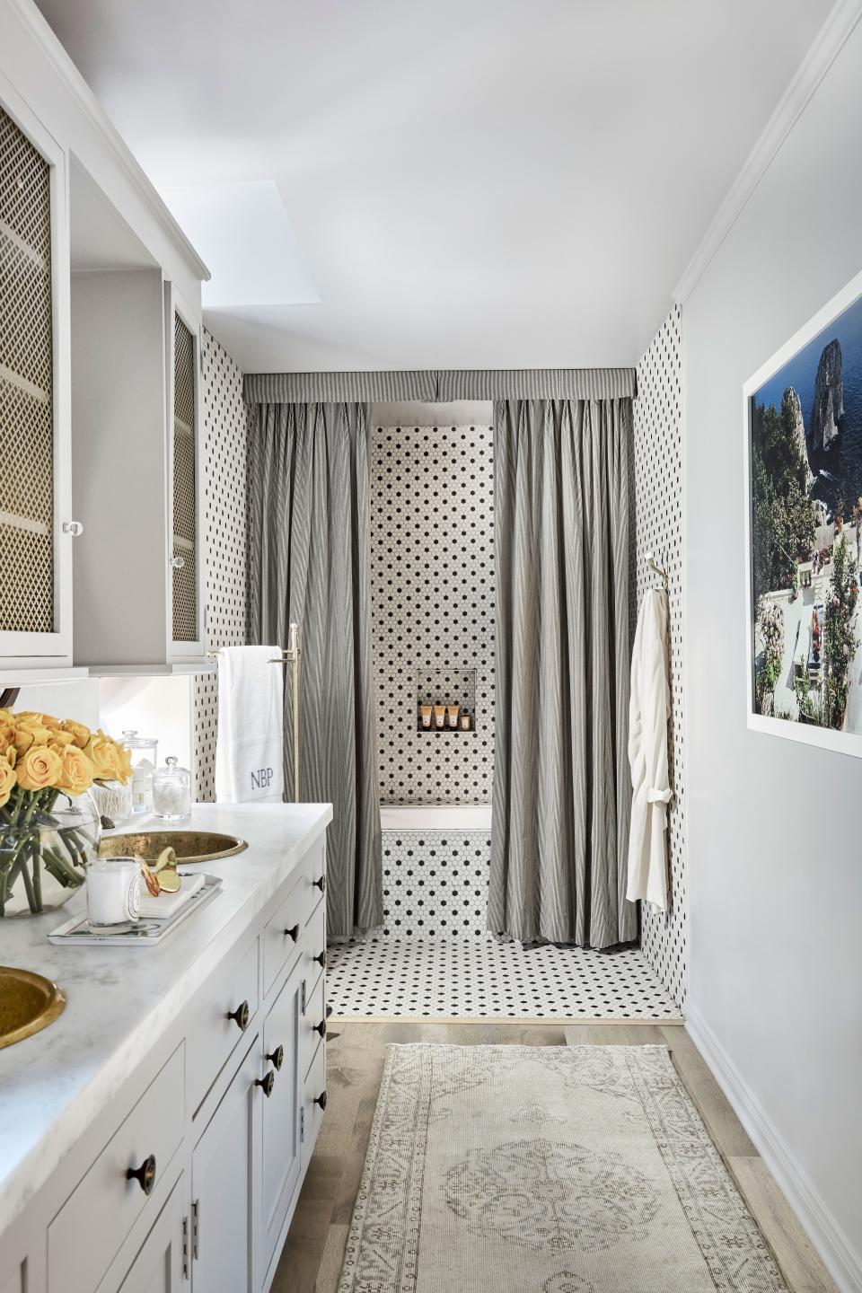 The curtains draping the bathtub are a “charming” feature original to the house, says Roxy, adding that two loveseats in the bathroom make for a “sweet moment.”