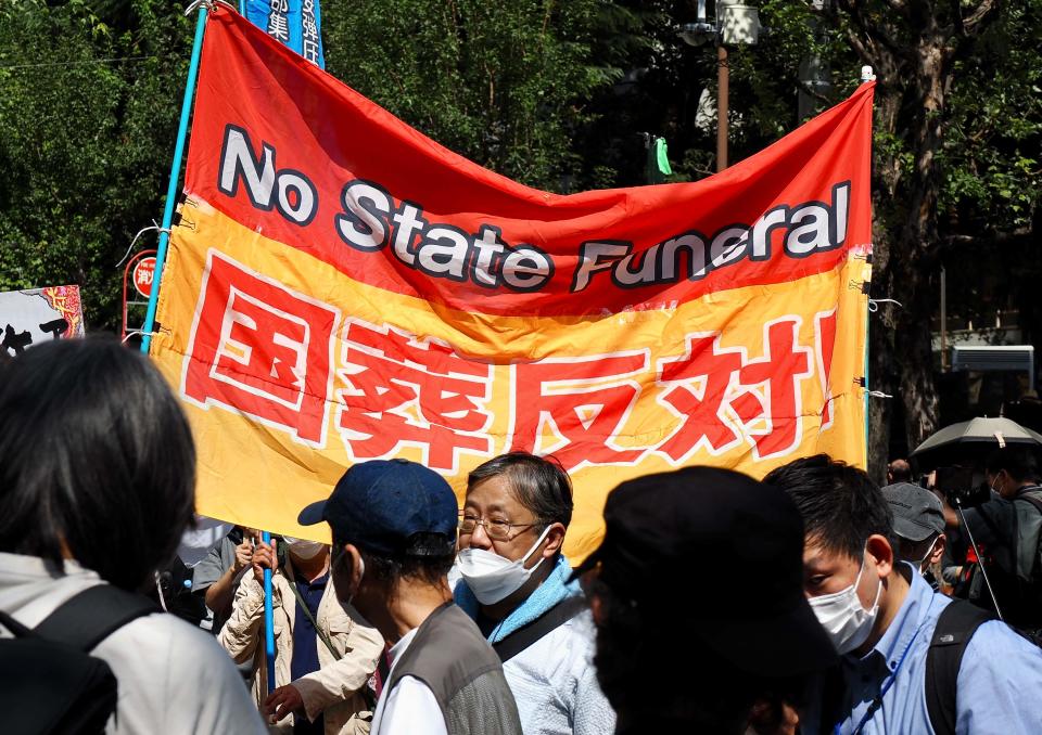 A protestor holds a placard against the state funeral of former Japanese prime minister Shinzo Abe (AFP via Getty Images)