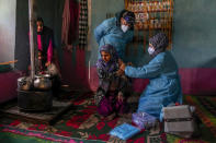 Kashmiri village girl Safia Banoo, receives vaccine for COVID-19 from Masrat Farid, a healthcare worker, as her family members warm themselves near a heater in Gagangeer, northeast of Srinagar, Indian controlled Kashmir, Jan. 12, 2022.(AP Photo/Dar Yasin)