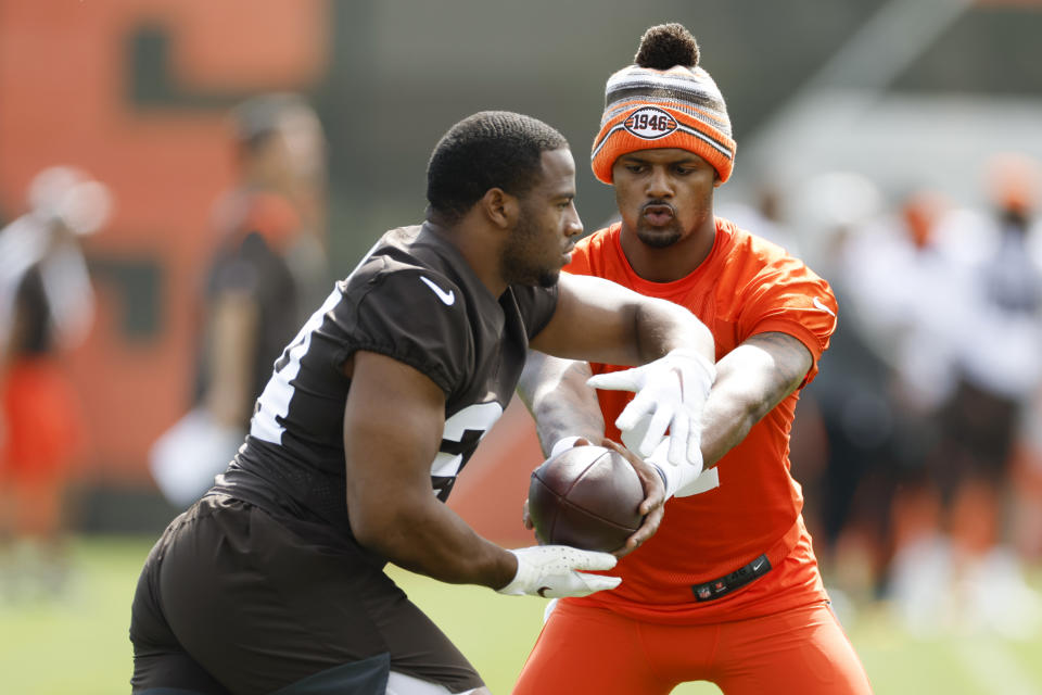 Cleveland Browns quarterback Deshaun Watson, right, hands off to Nick Chubb during NFL football practice at the team's training facility Wednesday, May 25, 2022, in Berea, Ohio. (AP Photo/Ron Schwane)