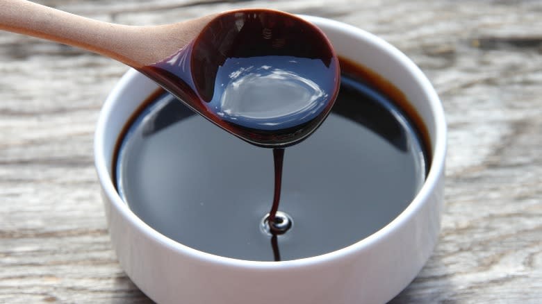 Molasses dripping from a wooden spoon into a dish