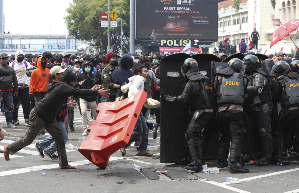 Police in riot gear try to block protesters from advancing towards the Presidential Palace during a rally in Jakarta, Indonesia, Thursday, Oct. 8, 2020. Thousands of enraged students and workers staged rallies across Indonesia on Thursday in opposition to a new law they say will cripple labor rights and harm the environment. (AP Photo/Achmad Ibrahim)