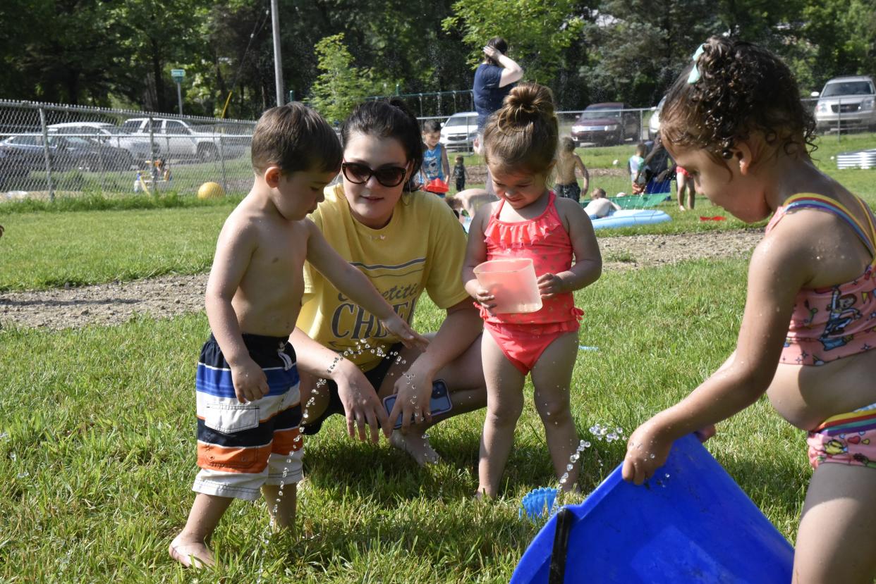 Maddie Kalinosky, a child care educator at Bright Light Early Care and Education, plays with children during "Water Day" activities on Tuesday, June 14, 2022 in Battle Creek, Mich.