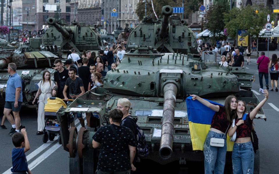 People walk in front of destroyed Russian tanks installed on Khreschatyk street in downtown of Kyiv