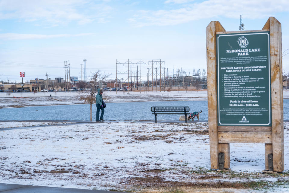 A woman and her dog enjoy walk at McDonald Lake near Coulter Street as Amarillo gets its first snow of the season Saturday afternoon.