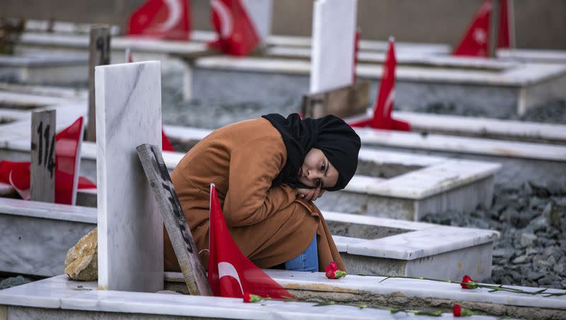 A girl sits next to a grave in a cemetery where some of the victims of the February 2023 earthquake are buried in Antakya, southern Turkey, on Tuesday, Feb. 6, 2024. Millions of people across Turkey on Tuesday mourned the loss of more than 53,000 friends, loved ones and neighbors in the country’s catastrophic earthquake a year ago.