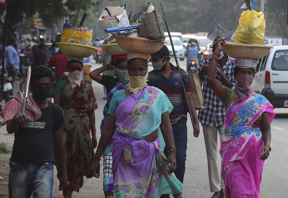 Construction laborers wearing masks as a precaution against the coronavirus walk on a street in Hyderabad, India, Saturday, April 24, 2021. Indian authorities are scrambling to get medical oxygen to hospitals where COVID-19 patients are suffocating from low supplies. The effort Saturday comes as the country with the world's worst coronavirus surge set a new global daily record of infections for the third straight day. The 346,786 infections over the past day brought India's total past 16 million. (AP Photo/Mahesh Kumar A.)