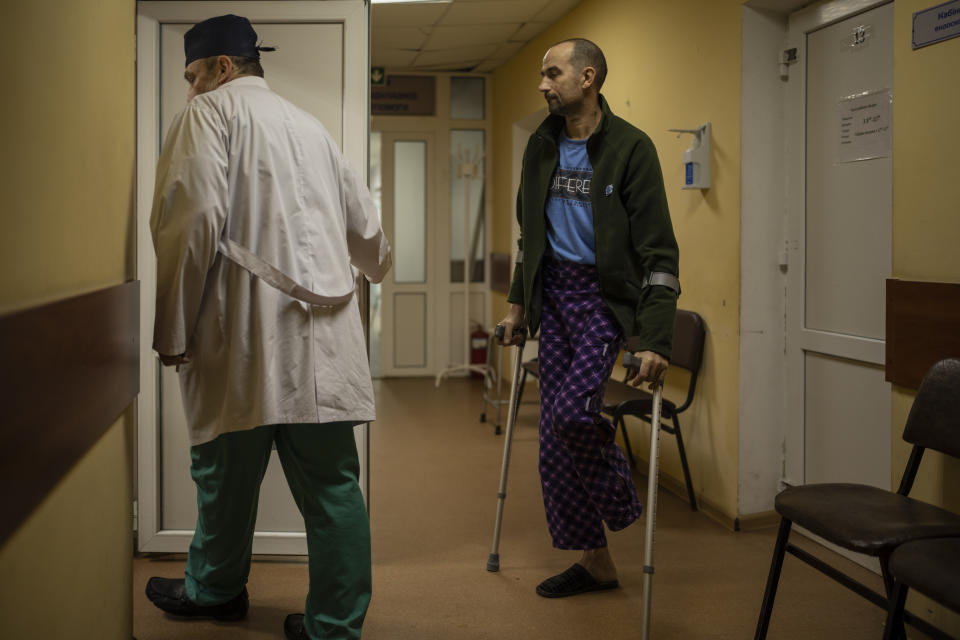 Landmine victim Oleksandr Kolisnyk follows Ukrainian doctor Yurii Kuznetsov in his office at the hospital in Izium, Ukraine, Sunday, Feb. 18, 2023. Russian attacks have devastated Ukraine's health care system, raining down explosions upon hospitals and ambulances at a rate of nearly two a day for the past year, according to a study that attempted to document each strike.(AP Photo/Vadim Ghirda)