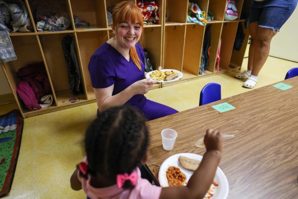 Savannah Seel, teacher of the eighteen-month-olds class, smiles as she eats lunch with one of the children at Lollipops daycare center.