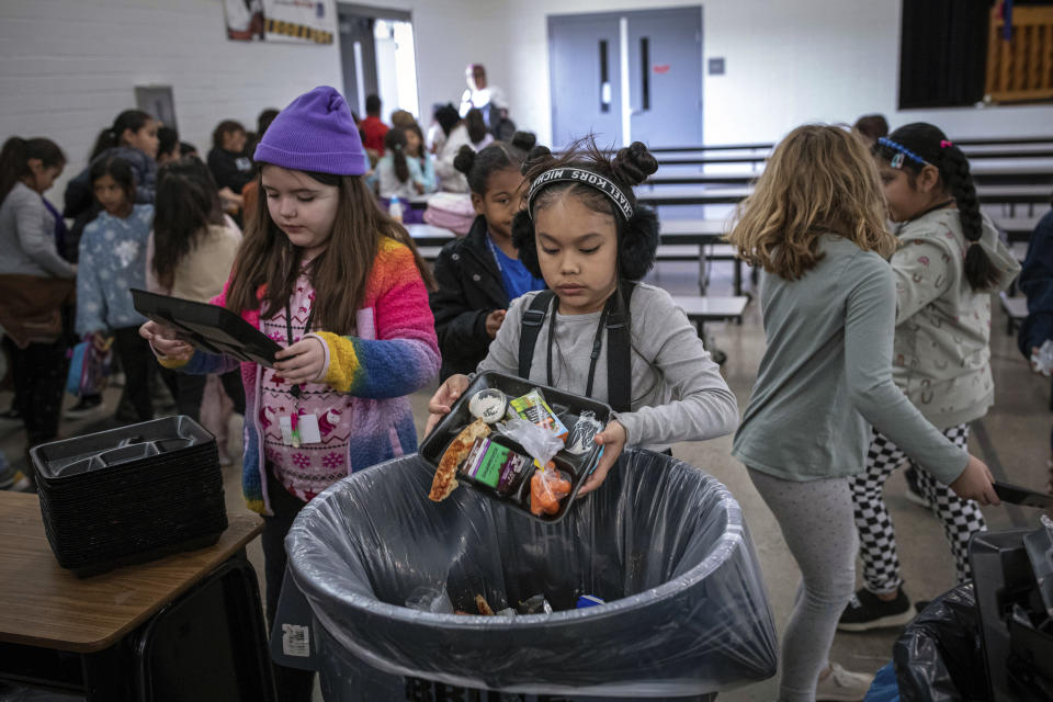 Students dispose of their unfinished food at the end of lunch break at Yavapai Elementary School in Scottsdale, Ariz., Dec. 12, 2022. Funding, labor and supply shortages have limited the school district's ability to cook and serve fresh food, making it more reliant on prepackaged, ready-to-eat items. (AP Photo/Alberto Mariani)