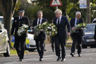 British Prime Minister Boris Johnson and Leader of the Labour Party Keir Starmer, second from left, carry flowers as they arrive at the scene where a member of Parliament was stabbed Friday, in Leigh-on-Sea, Essex, England, Saturday, Oct. 16, 2021. David Amess, a long-serving member of Parliament was stabbed to death during a meeting with constituents at a church in Leigh-on-Sea on Friday, in what police said was a terrorist incident. A 25-year-old man was arrested in connection with the attack, which united Britain's fractious politicians in shock and sorrow. (AP Photo/Alberto Pezzali)