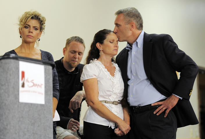 Thomas Teves, right, kisses his wife Caren Teves, center, at a press conference by families of victims of the Colorado theater shooting, in Aurora, Colo., on Tuesday, Aug. 28, 2012. Thomas and Caren Teves lost their son Alexander Teves, 24, in the shooting. Families of some of the 12 people killed in the Colorado theater shooting are upset with the way the millions of dollars raised since the tragedy are being distributed. (AP Photo/Chris Schneider)