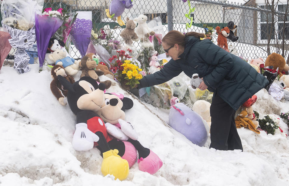 A woman places flowers at the site of a daycare centre in Laval, Quebec, Thursday, Feb. 9, 2023, where a bus crashed into the building killing two children. (Graham Hughes/The Canadian Press via AP)
