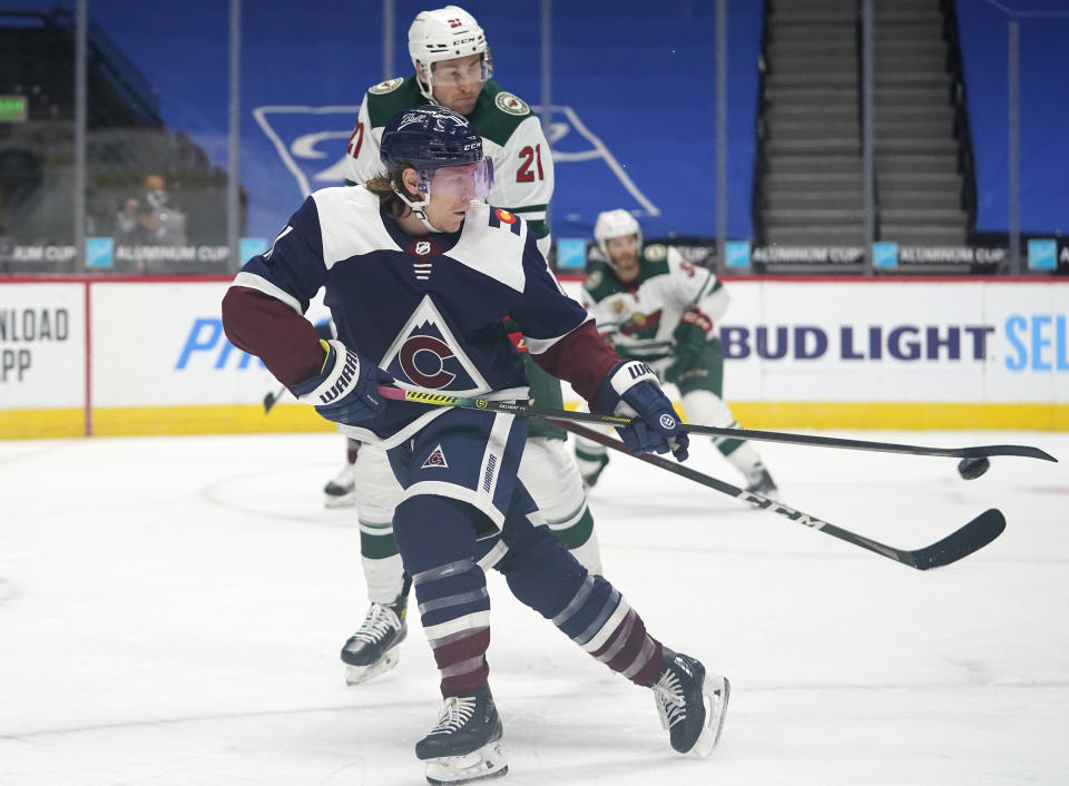 Colorado Avalanche left wing Matt Calvert, front, fields a pass as Minnesota Wild defenseman Carson Soucy covers in the first period of an NHL hockey game Wednesday, Feb. 24, 2021, in Denver. (AP Photo/David Zalubowski)