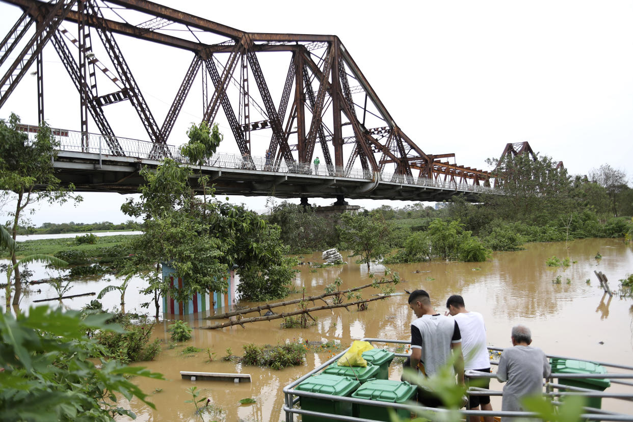 People watch the flooded Red river next to iconic Long Bien bridge, following Typhoon Yagi in Hanoi, Vietnam on Tuesday, Sept. 10, 2024. (AP Photo/Huy Han)