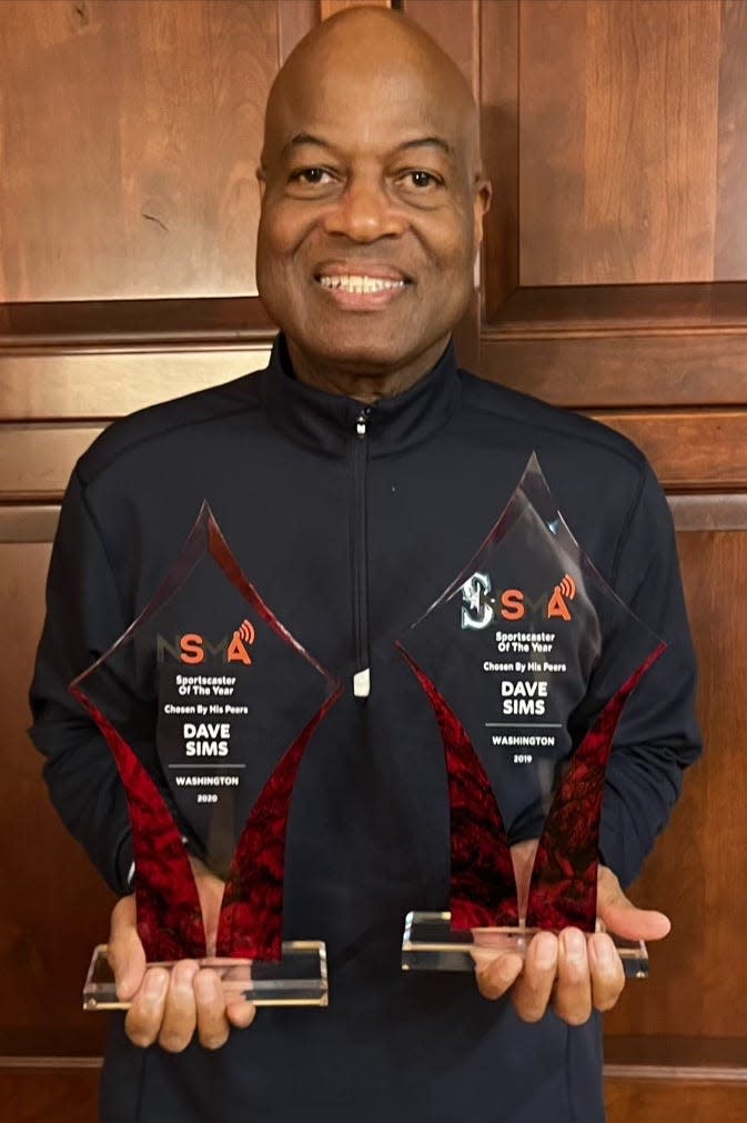Seattle Mariners play-by-play announcer Dave Sims holds up two of his three sportscaster of the year awards from the National Sports Media Association.