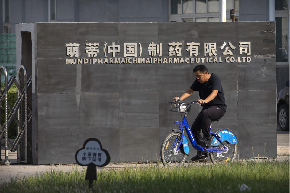 A man rides a bicycle past the entrance gate of a Mundipharma facility in an industrial park on the outskirts of Beijing, China on Sept. 27, 2019. As the Sackler's U.S. empire collapses, Mundipharma, which is also owned by the family, is using the same tactics to sell opioids in China. (AP Photo/Mark Schiefelbein)