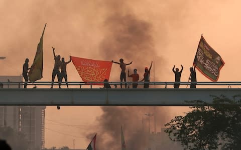 Protesters wave flags over a bridge - Credit: AP Photo/Hadi Mizban