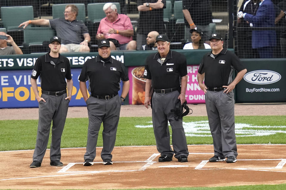 Umpire Joe West, second from right, stands with fellow umpires Nic Lentz, Bruce Dreckman and Dan Bellino as they watch a video tribute to West before a baseball game between the Chicago White Sox and the St. Louis Cardinals on Tuesday, May 25, 2021, in Chicago. West is set to break the record for most games as a major league umpire with No. 5,376 when he works the Tuesday's game. (AP Photo/Charles Rex Arbogast)