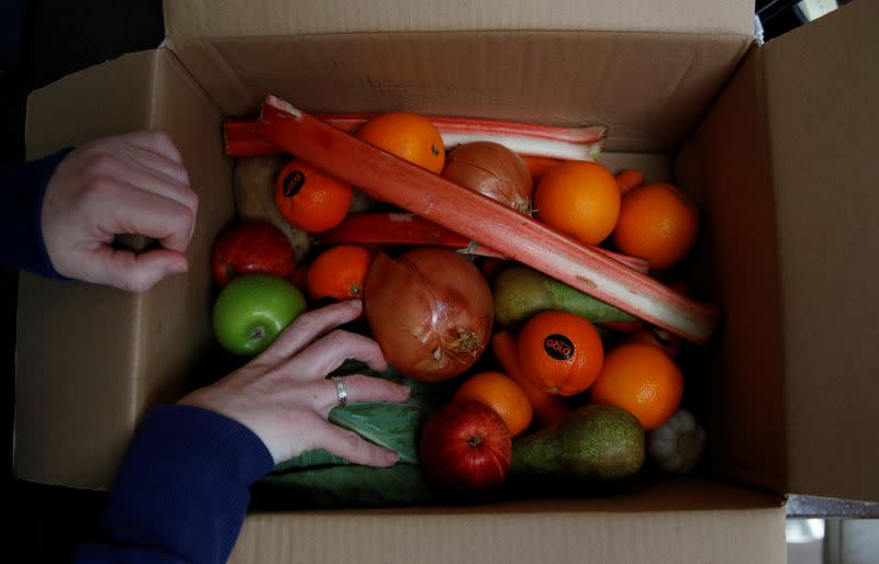 A woman unpacks a box of fruit and vegetables delivered to her door, as the spread of the coronavirus disease (COVID-19) continues, Manchester