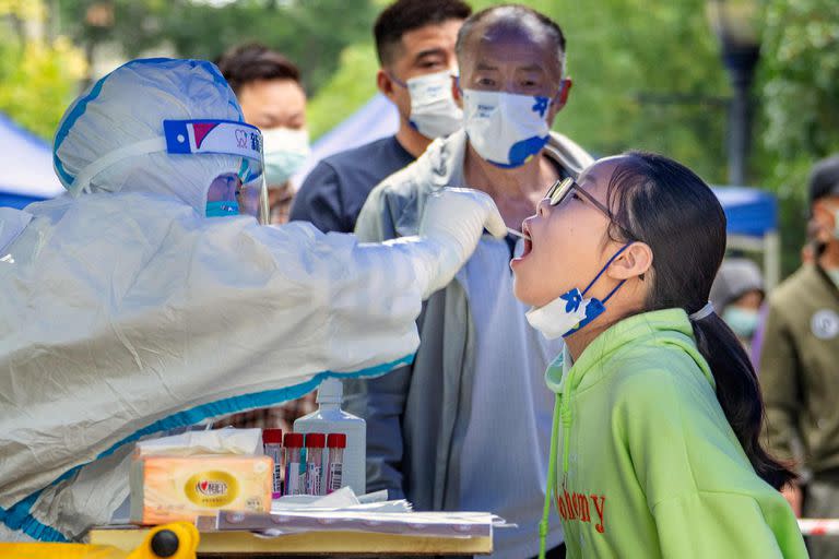 This photo taken on September 17, 2022 shows a health worker taking a swab sample from a young resident to be tested for the Covid-19 coronavirus in Chengdu in China's southwestern Sichuan province. - The Chinese megacity of Chengdu will on September 19 come out of a lockdown that had closed schools, disrupted businesses and forced millions to stay at home in large swathes of the city for over two weeks. (Photo by CNS / AFP) / China OUT