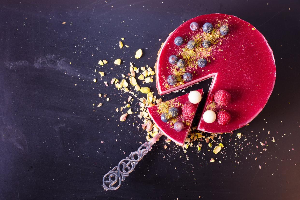 raspberry cake with fresh strawberries, raspberries, blueberry, currants and pistachios on wooden background