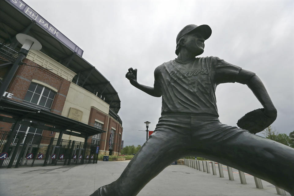 A statue of Atlanta Braves pitcher Phil Niekro stand outside Truist Park, home of baseball's Atlanta Braves, Tuesday, March 31, 2020, in Atlanta. The Braves were suppose to host their home opener on Friday, April 3, but the season's start was postponed by Major League Baseball because of the coronavirus pandemic. (Curtis Compton/Atlanta Journal-Constitution via AP)