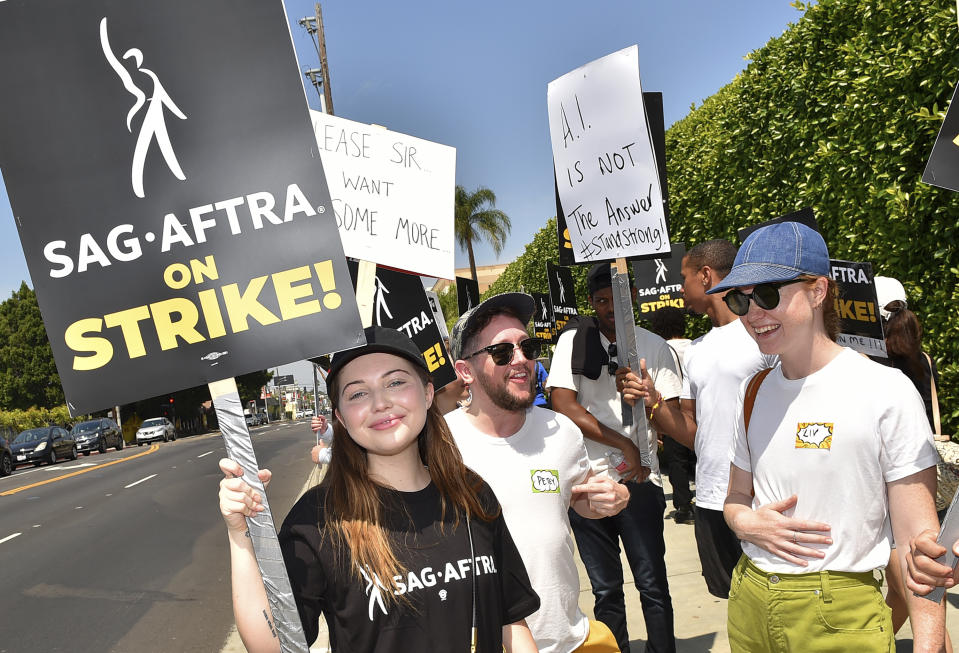 Actors Samantha Hanratty, left, and Liv Hewson, right, members of the cast of "Yellowjackets," carry signs on a picket line outside Paramount studios in Los Angeles on Monday, July 17, 2023. The actors strike comes more than two months after screenwriters began striking in their bid to get better pay and working conditions and have clear guidelines around the use of AI in film and television productions. (Jordan Strauss/Invision/AP)