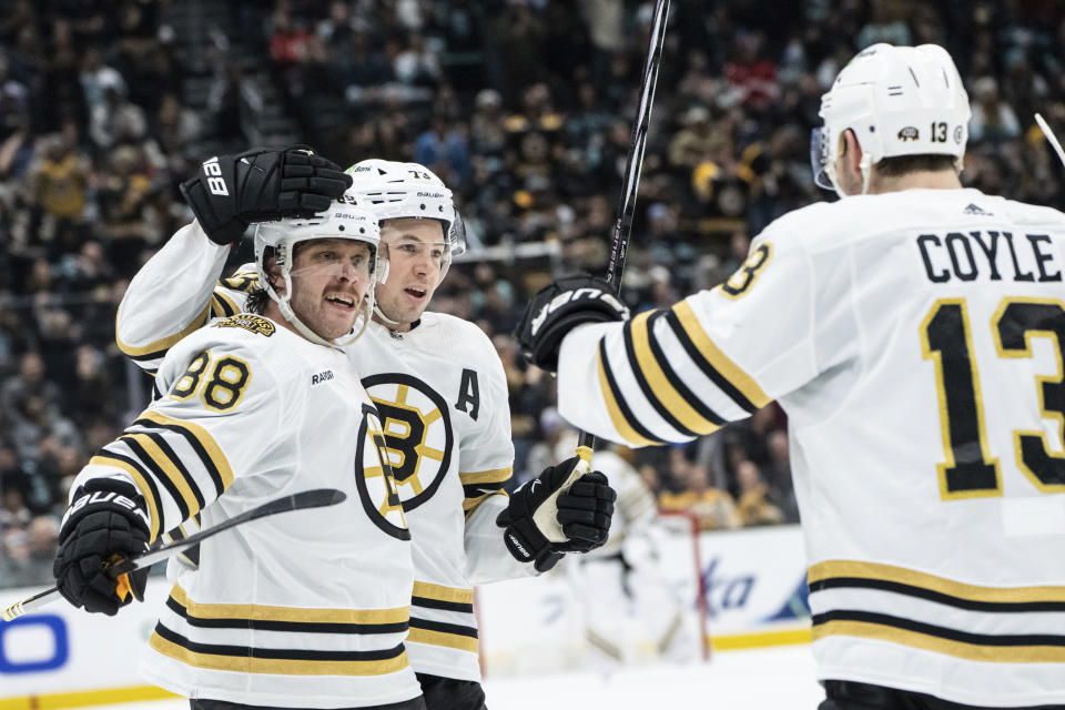 Boston Bruins forward David Pastrnak, left, celebrates with defenseman Charlie McAvoy and forward Charlie Coyle, right, after scoring his third goal during the third period of an NHL hockey game against the Seattle Kraken, Monday, Feb. 26, 2024, in Seattle. The Kraken won 4-3 in a shootout. (AP Photo/Stephen Brashear)