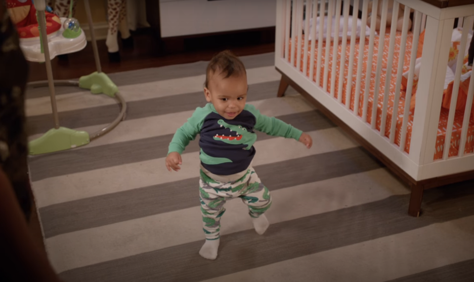 a baby walking by a crib