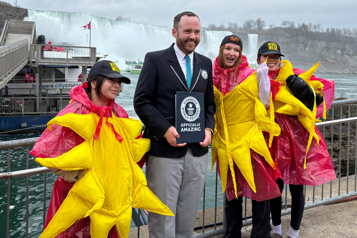 Guinness World Record adjudicator Mike Marcotte holds a pre-announcement as he poses with some of the 309 participants of the largest group of people dressed as the sun, before the total solar eclipse in Niagara Falls, Ontario, Canada April 8, 2024.  REUTERS/Jenna Zucker