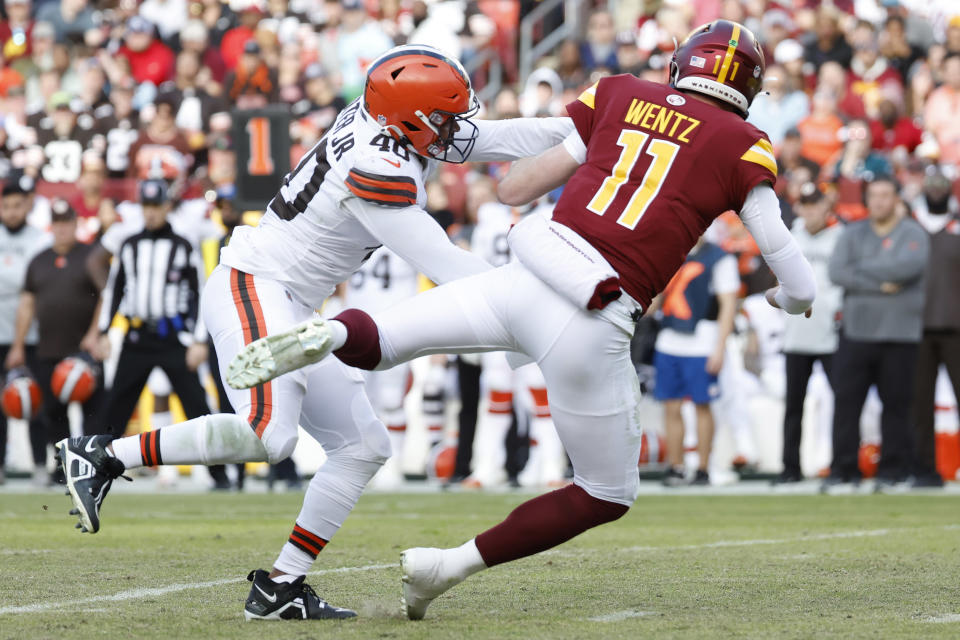 Washington Commanders quarterback Carson Wentz (11) is hit after throwing a pass by Cleveland Browns linebacker Jermaine Carter (40). Mandatory Credit: Geoff Burke-USA TODAY Sports