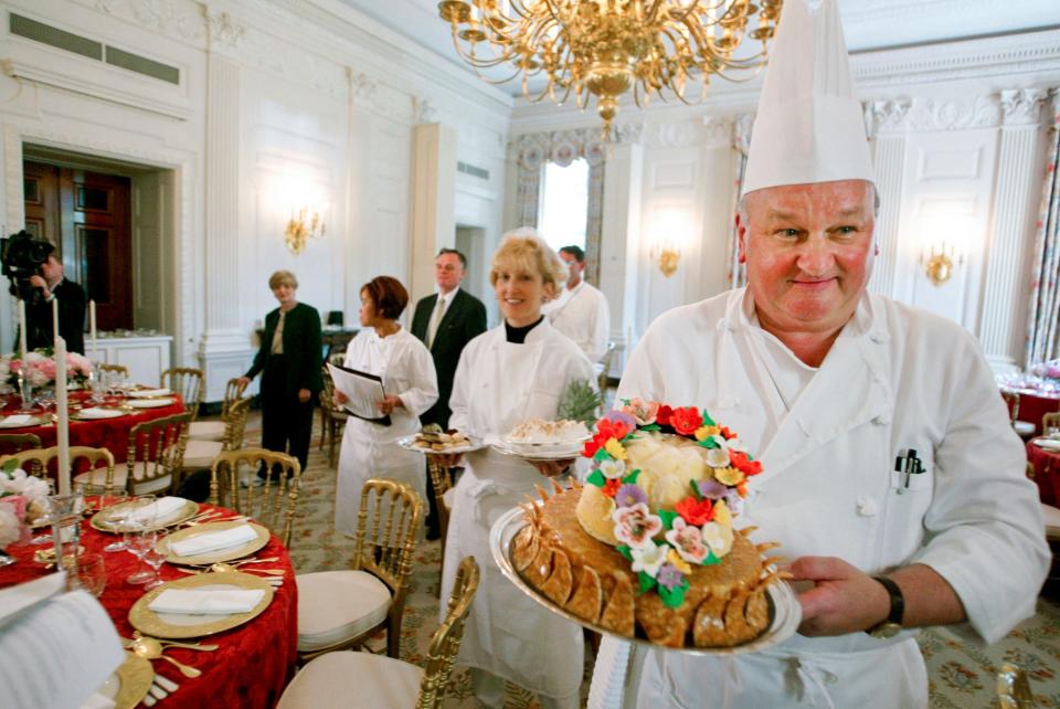 White House pastry chef Roland Mesnier, right, displays a mango coconut lei, the dessert for the dinner hosted by President George W. Bush for Philippine President Gloria Macapagal Arroyo, in the State Dining Room in the White House in Washington, May 19, 2003. Mesnier, a White House executive chef and who served five presidential administrations for roughly 25 years, died Friday, Aug. 26, 2022. 