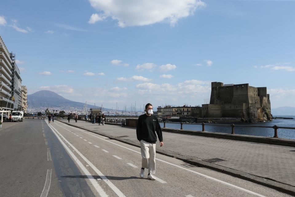 A man wearing a respiratory mask as part of precautionary measures against the spread of the new COVID-19 coronavirus, walks along the seafront by Castel dell'Ovo in Naples on March 10, 2020. (Credit: Carlo Hermann/AFP)