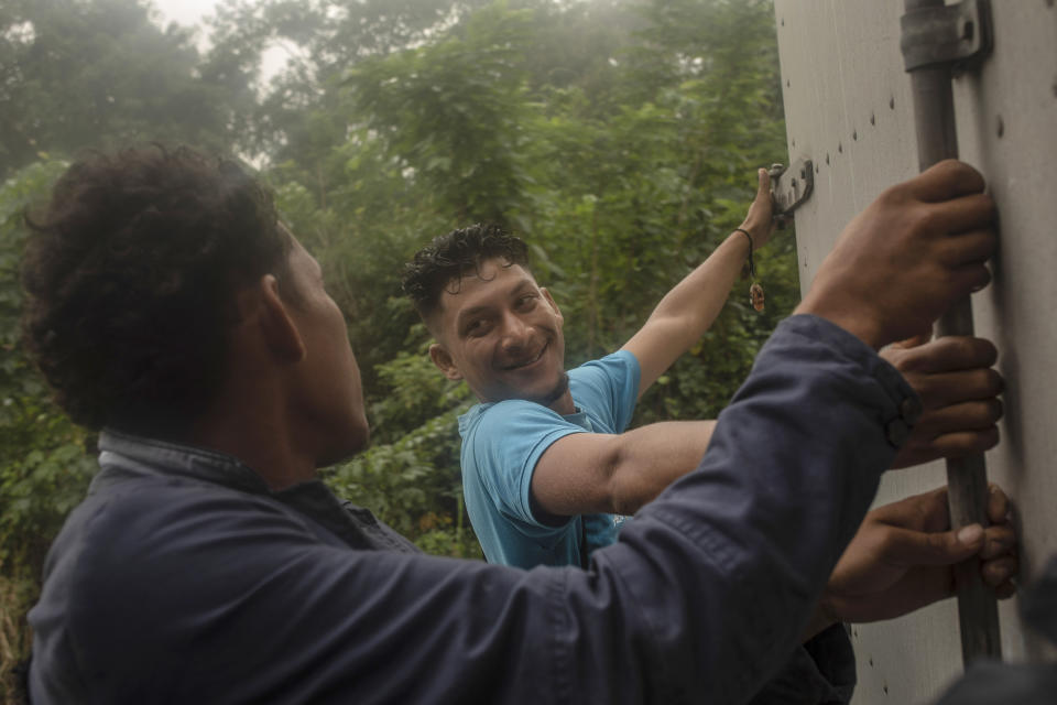 A couple of migrants hang on to the back of a truck as they travel north from the community of La Lima in southern Veracruz state, Mexico, Wednesday, Nov. 24, 2021. The United States and Mexico announced Thursday, Dec. 2, a deal to re-implement under court order a Trump-era policy known as “Remain in Mexico” at Mexico’s northern border that forced asylum seekers to wait out their cases inside Mexico. (AP Photo/Felix Marquez)