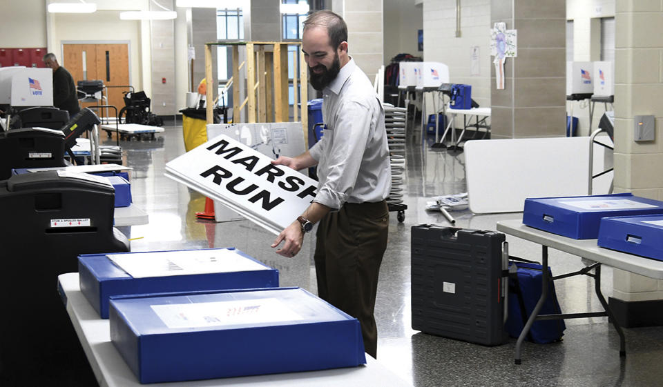 Keith Miller passes out signs with voting equipment in Ashland, Ky., Monday, Nov. 4, 2019, where twelve precincts will cast ballots during election day Tuesday. (Kevin Goldy/The Daily Independent via AP)