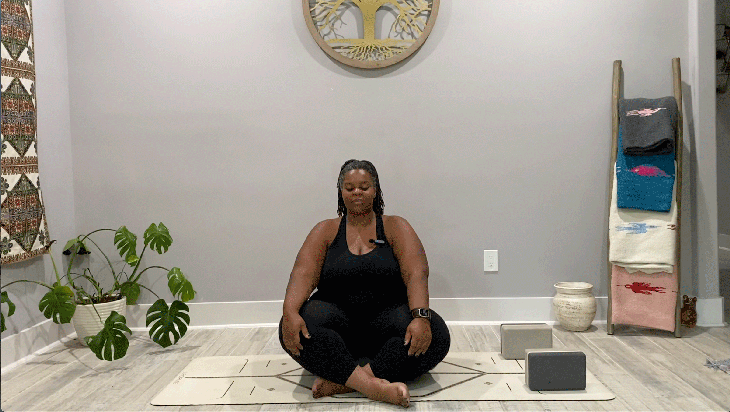 Woman seated cross-legged on a yoga mat beginning her slow flow 15-minute yoga practice