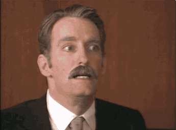 A old, mustachioed executive screams as the camera zooms across a boardroom table.